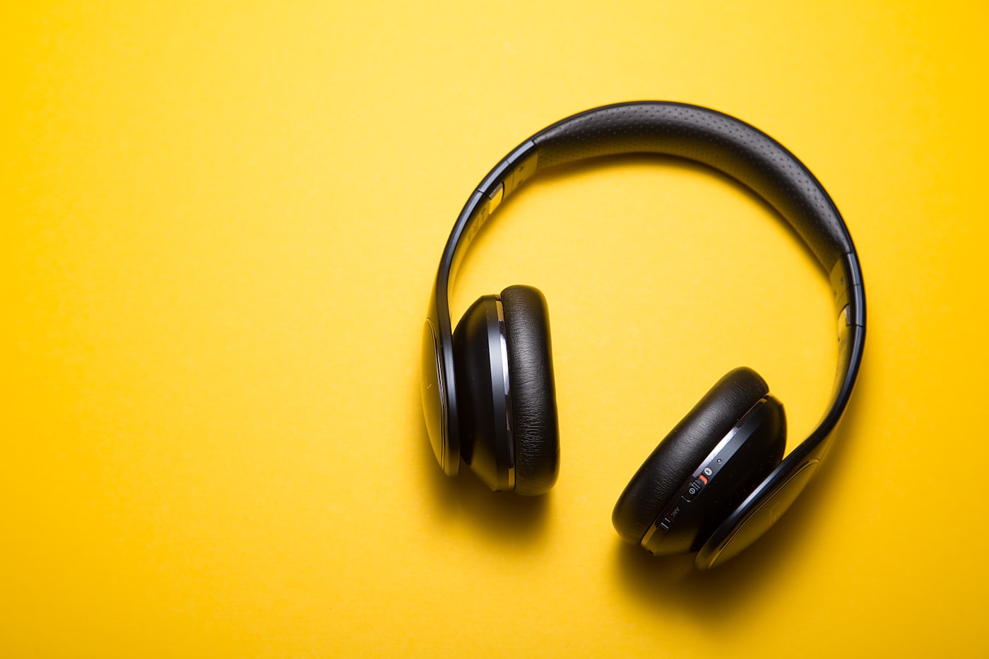 Over-ear headphones resting on a desk beside a notebook